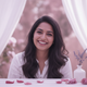 Close-up portrait of a smiling South Asian woman in her late 20s, exuding warmth and trustworthiness against a soft backgroun
